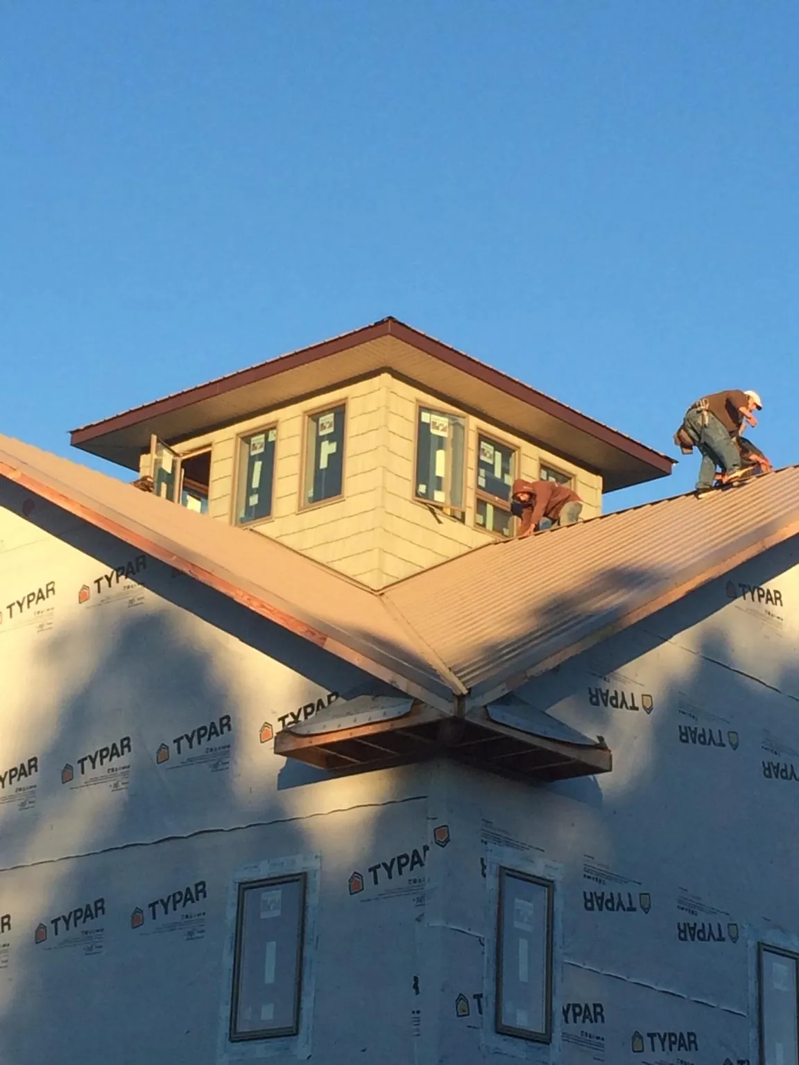 Roofers working around a rooftop cupola on a new metal roof at sunset — Roof Waterproofing in Galena by Roofing Brothers